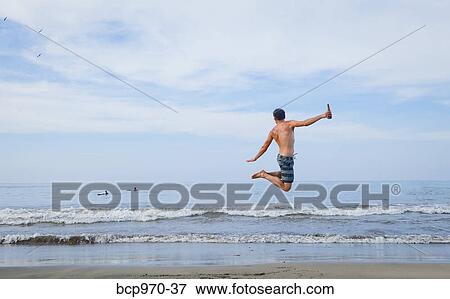 Stock Photo - Man leaping in air on beach. Fotosearch