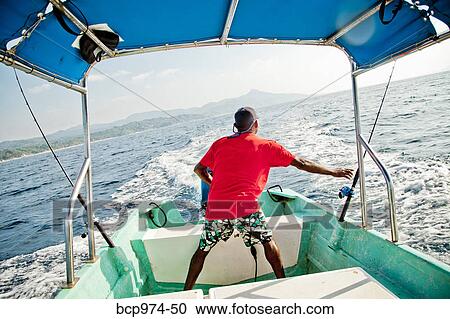 Stock Image - Man running fishing charter boat. Fotosearch
