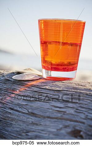 Orange cup on driftwood log View Large Photo Image Stock Photography - Orange cup on driftwood log. Fotosearch