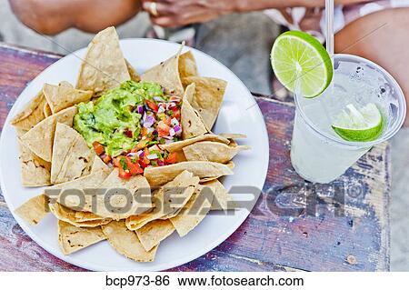 Plate of nachos and margarita on table View Large Photo Image Stock Photograph - Plate of nachos and margarita on table. Fotosearch