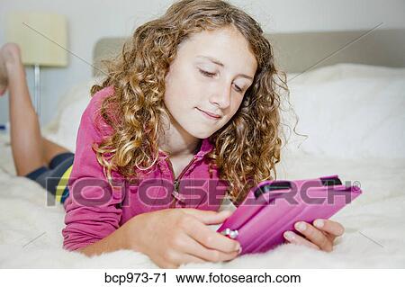 Teen girl on bed with tablet View Large Photo Image Stock Image - Teen girl on bed with tablet. Fotosearch