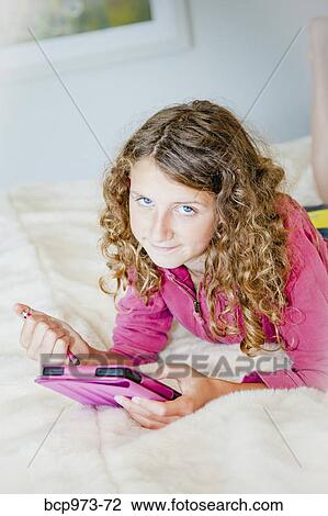 Teen girl on bed with tablet View Large Photo Image Stock Image - Teen girl on bed with tablet. Fotosearch