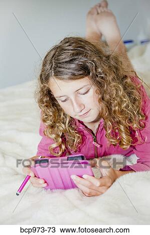 Teen girl on bed with tablet View Large Photo Image Stock Image - Teen girl on bed with tablet. Fotosearch