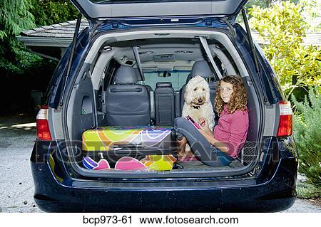 Stock Image - Teen girl with shopping bags and dog in car. Fotosearch