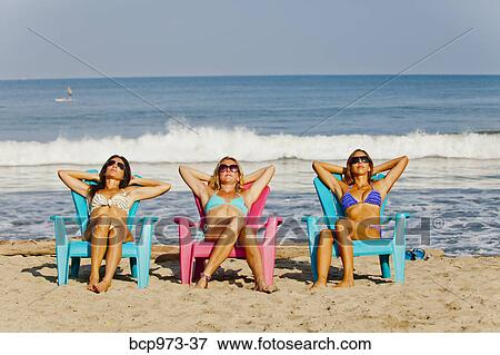 Three women lounging on beach chairs View Large Photo Image Stock Photo - Three women lounging on beach chairs. Fotosearch