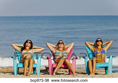 Three women lounging on beach chairs View Large Photo Image Stock Photo - Three women lounging on beach chairs. Fotosearch
