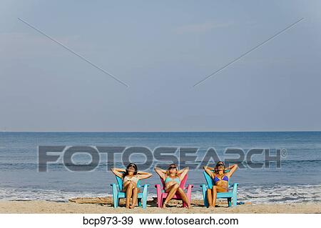 Three women lounging on beach chairs View Large Photo Image Stock Photo - Three women lounging on beach chairs. Fotosearch