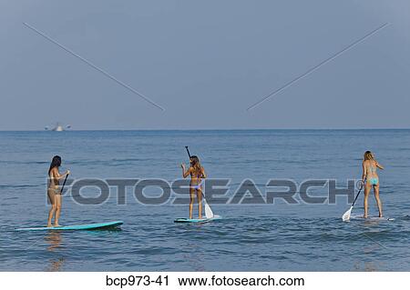 Three women on paddle boards View Large Photo Image Stock Image - Three women on paddle boards. Fotosearch