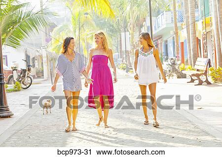 Stock Image - Three women shopping in seaside town. Fotosearch