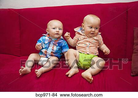Two babies on red sofa View Large Photo Image Picture - Two babies on red sofa. Fotosearch