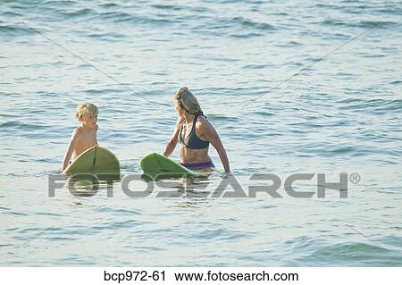 Woman and boy on surfboards in water View Large Photo Image Stock Image - Woman and boy on surfboards in water. Fotosearch