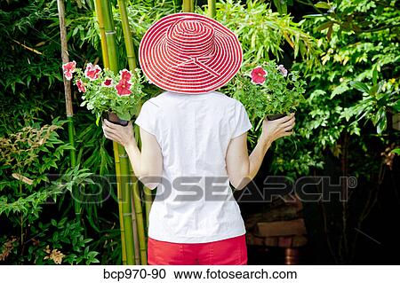 Stock Image - Woman holding plants outdoors. Fotosearch