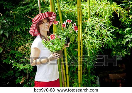 Stock Photo - Woman holding plants outdoors. Fotosearch