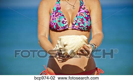 Woman in bikini holding shells View Large Photo Image Stock Image - Woman in bikini holding shells. Fotosearch