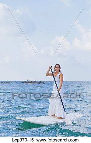 Woman in white dress riding paddle board View Large Photo Image Stock Photography - Woman in white dress riding paddle board. Fotosearch