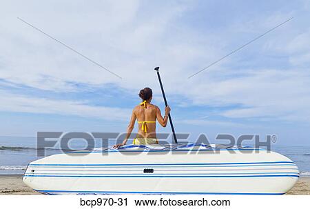 Woman on beach with paddle board View Large Photo Image Stock Image - Woman on beach with paddle board. Fotosearch