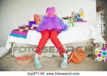 Picture - Woman on bed surrounded by shopping bags. Fotosearch