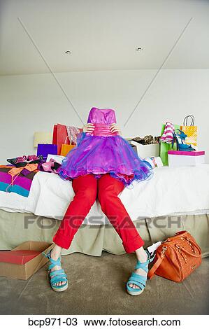Stock Image - Woman on bed surrounded by shopping bags. Fotosearch