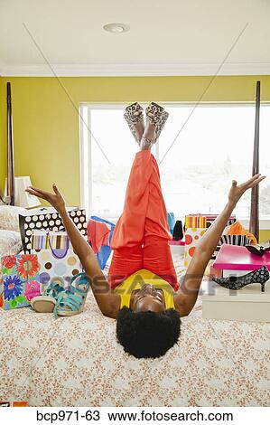 Stock Image - Woman on bed with shopping bags and shoes. Fotosearch