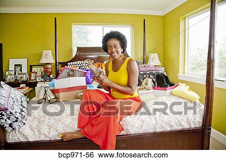 Stock Photograph - Woman on bed with shopping bags and shoes. Fotosearch