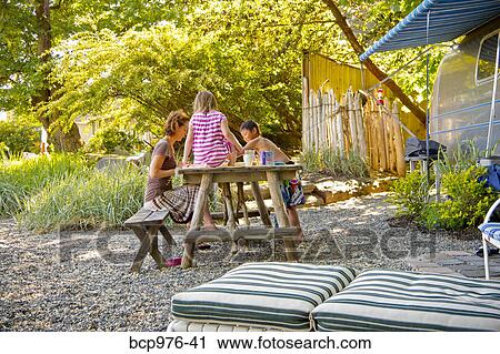 Woman playing board game with children at picnic table View Large Photo Image Stock Image - Woman playing board game with children at picnic table. Fotosearch