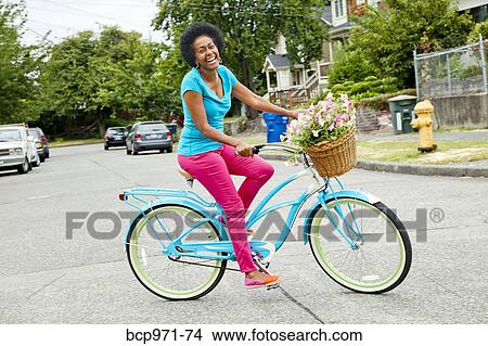 Woman riding retro bicycle with flower basket View Large Photo Image Picture - Woman riding retro bicycle with flower basket. Fotosearch