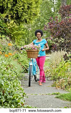 Woman riding retro bicycle with flower basket View Large Photo Image Stock Image - Woman riding retro bicycle with flower basket. Fotosearch