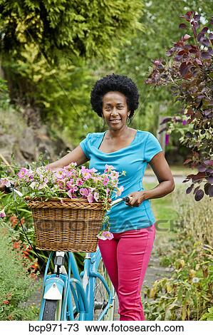 Woman riding retro bicycle with flower basket View Large Photo Image Stock Image - Woman riding retro bicycle with flower basket. Fotosearch