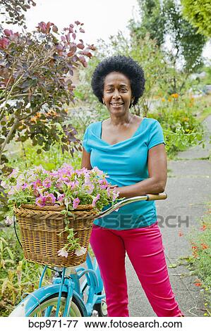 Woman riding retro bicycle with flower basket View Large Photo Image Stock Photo - Woman riding retro bicycle with flower basket. Fotosearch