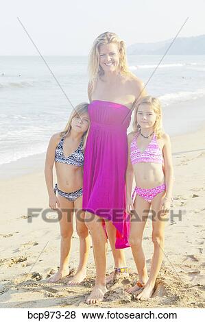 Stock Photo - Woman with two girls standing on beach. Fotosearch