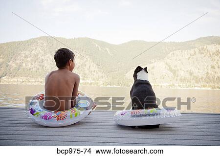 Young boy and dog wearing float rings on dock View Large Photo Image Picture - Young boy and dog wearing float rings on dock. Fotosearch