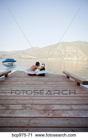 Young boy and dog wearing float rings on dock View Large Photo Image Stock Image - Young boy and dog wearing float rings on dock. Fotosearch