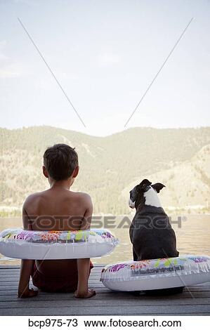 Young boy and dog wearing float rings on dock View Large Photo Image Stock Image - Young boy and dog wearing float rings on dock. Fotosearch