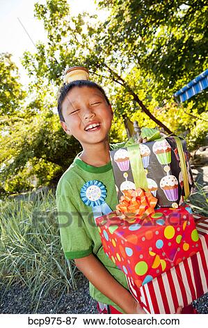 Stock Photo - Young boy in birthday hat with presents. Fotosearch