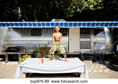 Young boy on picnic table in front of camper View Large Photo Image Stock Photo - Young boy on picnic table in front of camper. Fotosearch