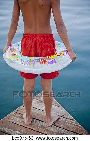Young boy wearing float ring on dock View Large Photo Image Stock Image - Young boy wearing float ring on dock. Fotosearch
