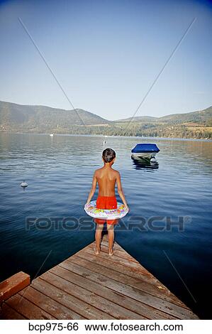 Stock Photograph - Young boy wearing float ring on dock. Fotosearch