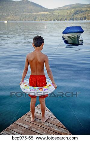 Stock Photography - Young boy wearing float ring on dock. Fotosearch