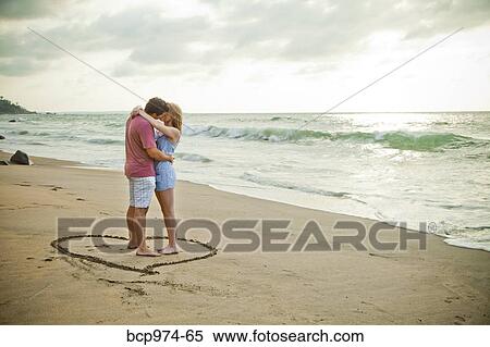 Young couple standing in heart design on beach View Large Photo Image Stock Photography - Young couple standing in heart design on beach. Fotosearch