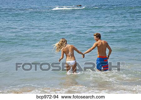 Young man and woman standing in surf View Large Photo Image Picture - Young man and woman standing in surf. Fotosearch