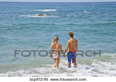 Young man and woman standing in surf View Large Photo Image Stock Photography - Young man and woman standing in surf. Fotosearch