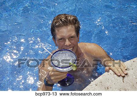 Young man in pool holding cocktail View Large Photo Image Stock Image - Young man in pool holding cocktail. Fotosearch