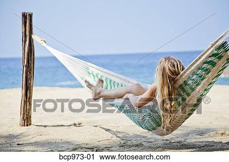 Stock Image - Young woman in hammock on beach. Fotosearch