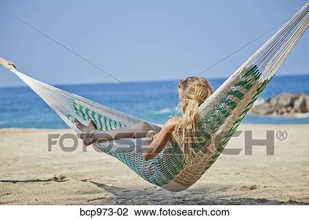 Stock Image - Young woman in hammock on beach. Fotosearch