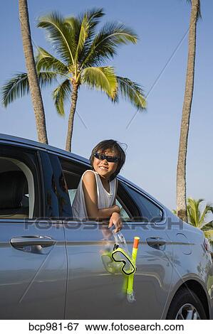 Stock Photo - Boy holding a scuba mask and snorkel leans out a car window. Fotosearch