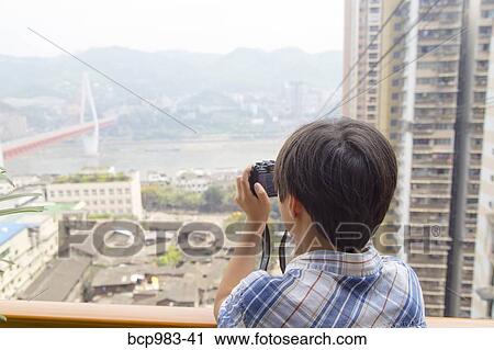 Stock Image - "Boy photographing the Yangtze river cable car, Chongqing, China". Fotosearch