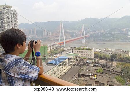 Stock Image - "Boy photographing the Yangtze river cable car, Chongqing, China". Fotosearch