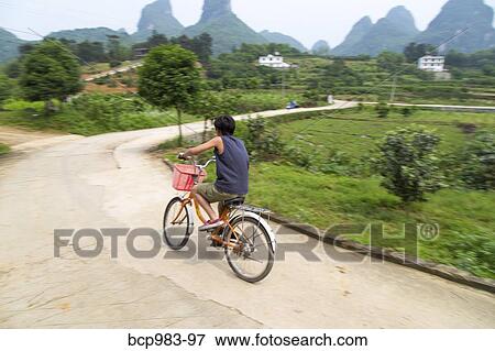 Stock Photo - "Boy rides a bicycle in the Yangshuo countryside, Yangshuo, China". Fotosearch
