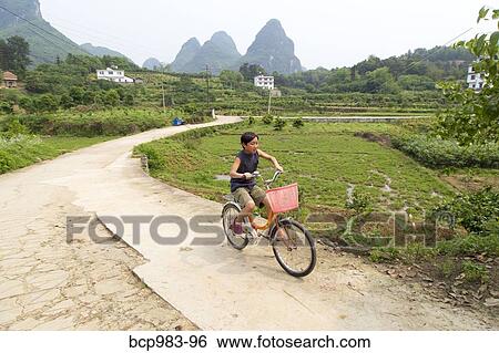 Stock Photograph - "Boy rides a bicycle in the Yangshuo countryside, Yangshuo, China". Fotosearch