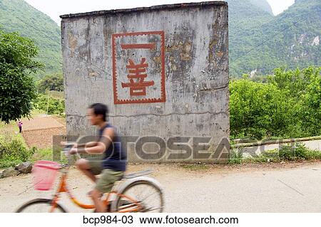 "Boy rides a bicycle past a ""one good deed"" sign in the countryside, Yangshuo, China" View Large Photo Image Stock Image - "Boy rides a bicycle past a ""one good deed"" sign in the countryside, Yangshuo, China". Fotosearch
